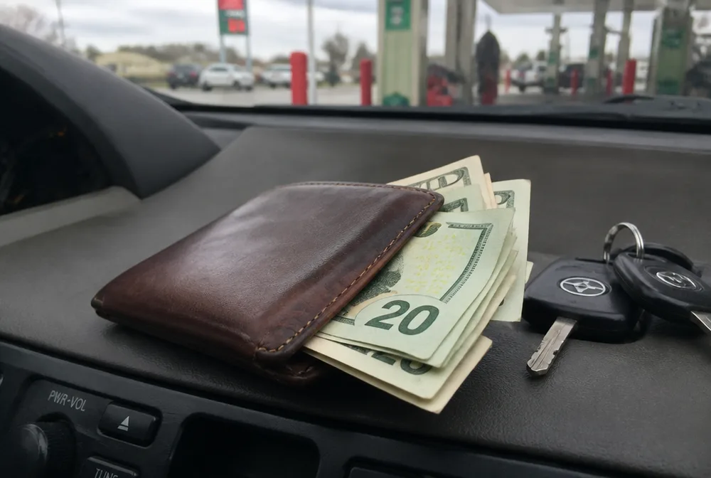 Cash and car keys on the dashboard — money saved at the pump